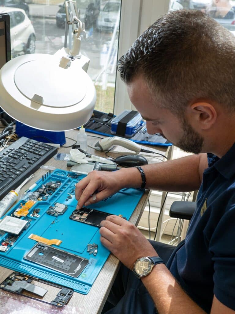 Photo d'un technicien de la société Avegott en train de réparer un téléphone pro reconditionné.