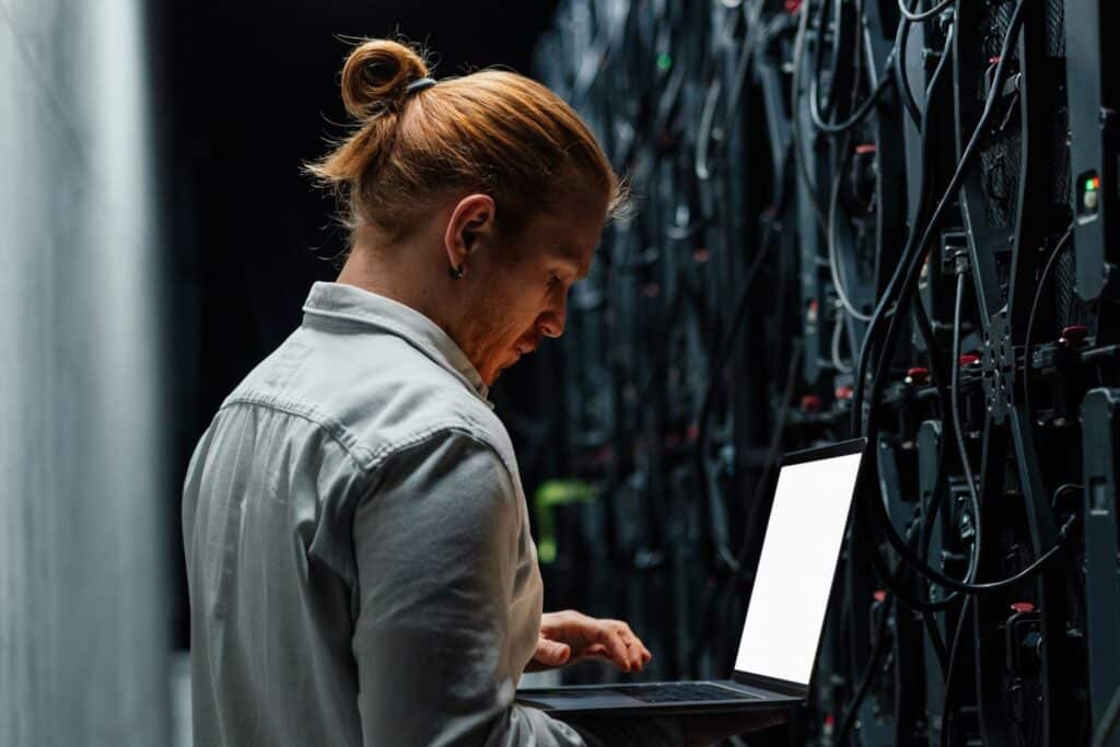 Photo d'un collaborateur dans une baie informatique pour présenter les différents mériers et expertises du Groupe Sincrone et de Sincrone IT.